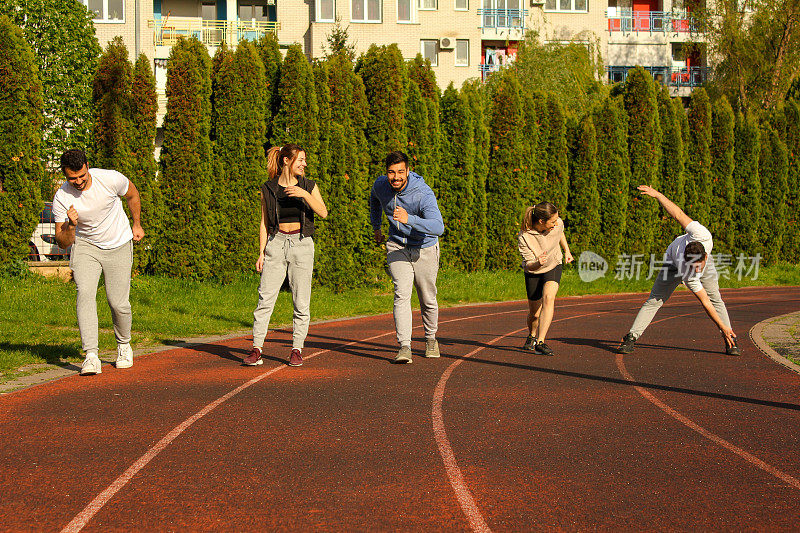 A group of friends preparing to start running on a track in a public park